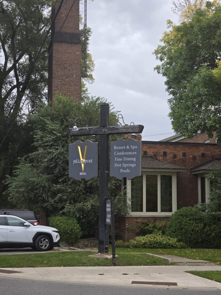 a sign on a pole in front of a brick building Pillar_and_Post-Niagara-on-the-Lake-transportation-from-toronto-pearson-airport